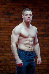 Strong Athletic Man Fitness Model Torso showing six pack abs. on the background of red brick wall