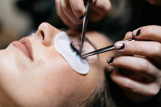 Young woman getting lash extension cosmetology laying down in small business studio