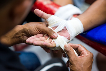 Muay Thai or Thai boxing fighter putting bandage on the hands preparing to fight