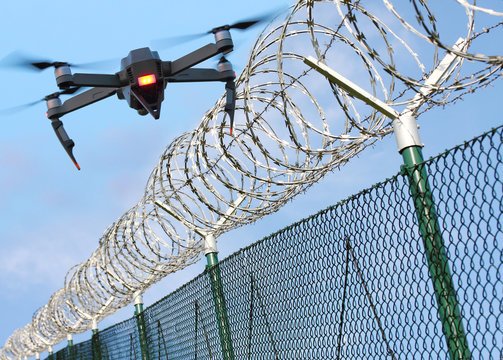 Fototapeta Drone monitoring barbed wire fence on state border or restricted area. Modern technology for security.