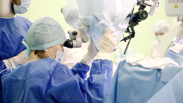 chief surgeon woman is correcting place of new modern laser apparatus, surgeons are consulting