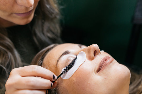 Young woman getting lash extension cosmetology laying down in small business studio