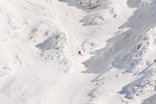 Male skier freeriding off piste through a snow couloir