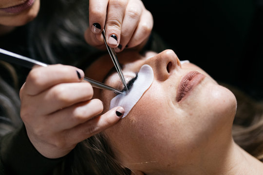 Young woman getting lash extension cosmetology laying down in small business studio