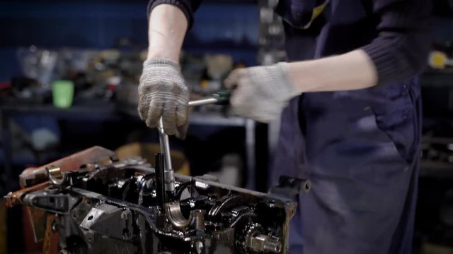 Close up shot of a young mechanic working with a car engine in the garage.