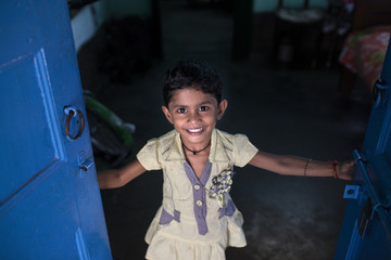 A little kid holding blue colored door,smiling and looking at camera