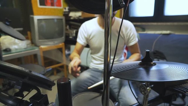 Drummer jamming in background on his electric drums, cymbals in foregound.
