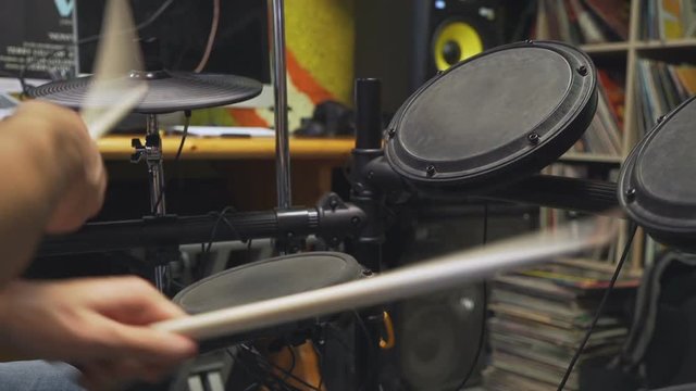 Drum sticks beating on electric drums, camera moving from bottom to top.