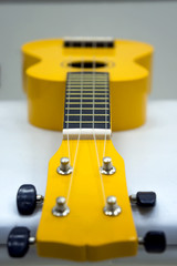 Yellow ukulele, soft focus on white background