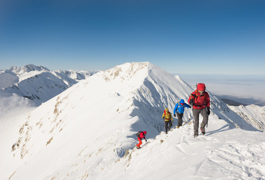 Group of hikers ascending on snow-capped mountain peak