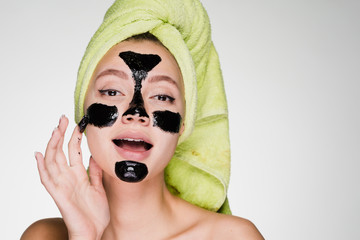young girl with a towel on her head puts on face mask