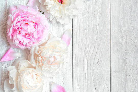pink and white peony flowers on white wooden table. top view with copy space