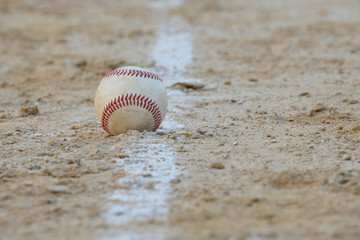 Fototapeta na wymiar A baseball sits right on the foul line on a sandy baseball field