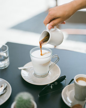 Hand pouring coffee to milk