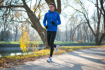 Young Sports Man Running in the Park in Cold Sunny Autumn Morning. Healthy Lifestyle and Sport...