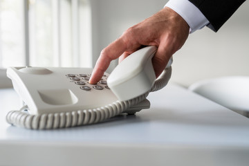 Male hand dialing a telephone number in order to make a phone call