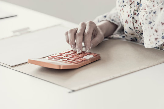 Female accountant calculating on orange desktop calculator