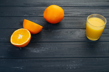 Glass of orange juice on wooden table, on wood plants background, fresh drink