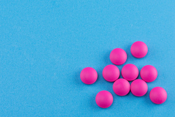 pink pills on blue background with copy space