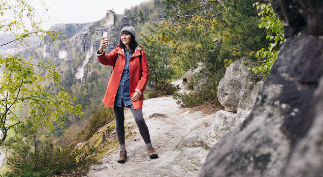 Cute Female Caucasian Hiker in Red Raincoat Taking Selfie