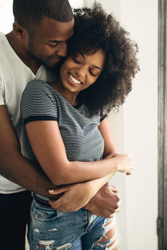 Young black couple embracing at home