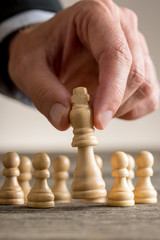 Businessman playing chess moving the king piece
