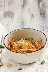 Homemade Thai Green Papaya Salad in a white bowl, selective focus