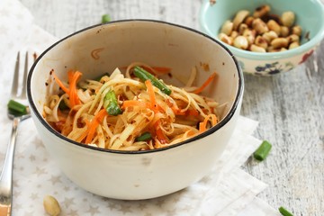 Homemade Thai Green Papaya Salad in a white bowl, selective focus