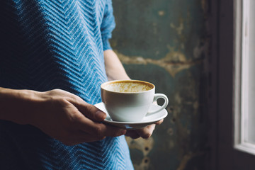 Keep in your hands an empty cup of coffee on rustic background