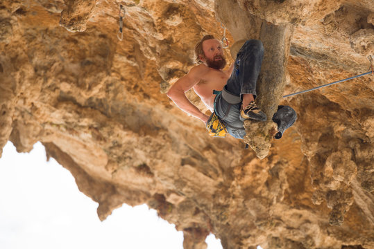 Portrait of man rock climber hanging on stalactite