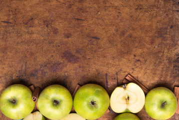 Green apples with cinnamon on the old wooden background. Autunm fruits. Top view. Flat lay.