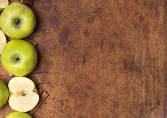 Green apples with cinnamon on the old wooden background. Autunm fruits. Top view. Flat lay.