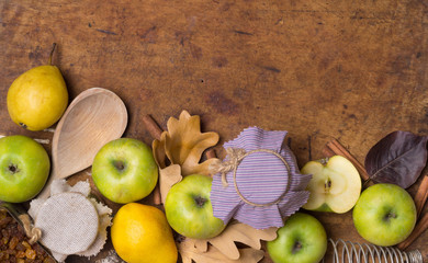 Autumn fruit background. Thanksgiving seasonal fruit. Stylish composition of green apple, oak leaves, pear, cinnamon, raisins, fabric cover, spoon, whisk. Old wood. Flat lay. Top view.