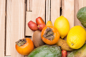 Fruit background. Mango kiwi pear dates persimmons lemon banana. Light Wooden Board background. The wooden box. Top view . Close up.