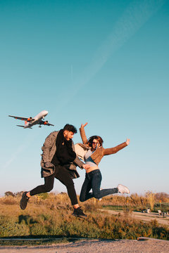 Couple jumping with a plane in the sky