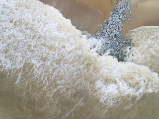 Aerial top view of sea waves hitting rocks on the beach in Pantai cahaya bulan, kota bharu, kelantan, malaysia
