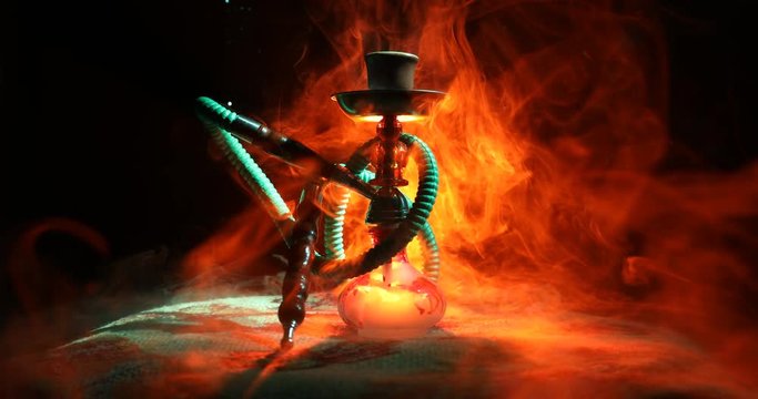 Hookah hot coals on shisha bowl on orange (like fire) clouds of steam on dark background. Stylish oriental shisha. Shisha Concept. On rotating display. 