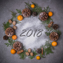 Merry Christmas and Happy New Year background. Christmas wreath with snow fir cones tangerines spruce cinnamon nuts. Flat lay. Copy space. The inscription 2018