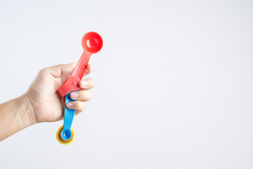 Hand holding set of measuring spoons made of colored plastic