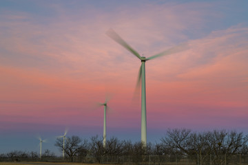 Sunrise lighting up some windmills and the sky behind them - 187553287