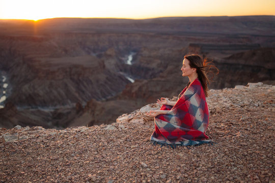 Woman with inner peace meditating at dawn dusk in mountains with