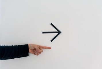 Isolated hand pointing out for something with black arrow on white wall