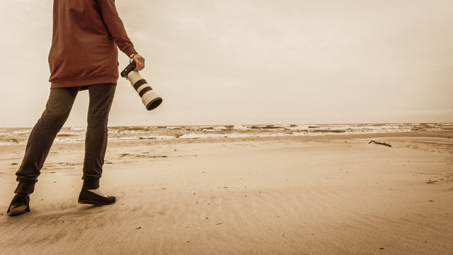 Woman walking on beach with camera