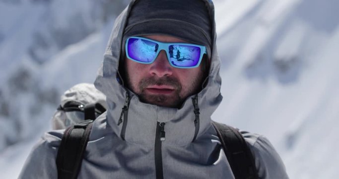 Climber mountaineer man portrait on snowy mount top in sunny day.Mountaineering ski activity. Skier people winter snow sport in alpine mountain outdoor.Front view.Slow motion 60p 4k video