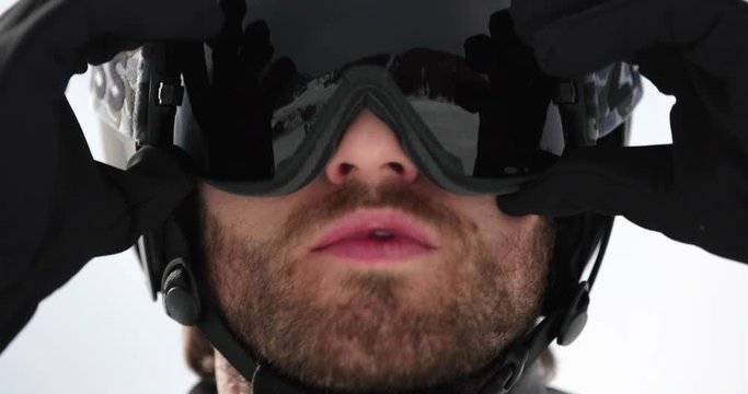 Man face detail adjusting helmet preparing for skiing.Mountaineering ski activity. Skier people winter sport in alpine mountain outdoor.Front view.Slow motion 60p 4k video