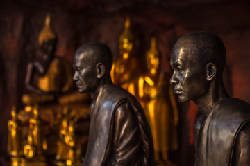 Naklejka premium Buddhist monks statues symbol of peace and serenity at Wat Phu Tok temple, Thailand, asceticism and meditation, buddhist art work