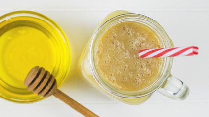 Freshly made smoothies with mango, banana, orange, honey and cereal on a white wooden table. The view from the top.