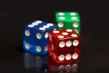 Red,blue and green dice on black background
