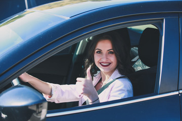 Woman driving car and showing thumb up