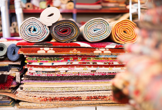Carpets of different colours in stack at carpet store